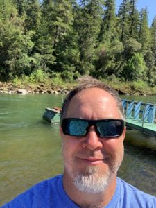 Man wearing blue shirt and sunglasses in front of the Rogue River